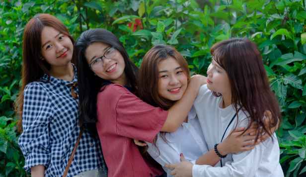 four women wearing shirts standing beside green leaf plants